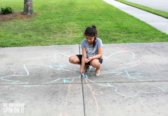 alphabet-sidewalk-chalk-game-chicka-chica-boom-boom - The Educators' Spin On It Child writing letters with sidewalk chalk onto Chicka Chicka Boom Boom book inspired Coconut Tree.