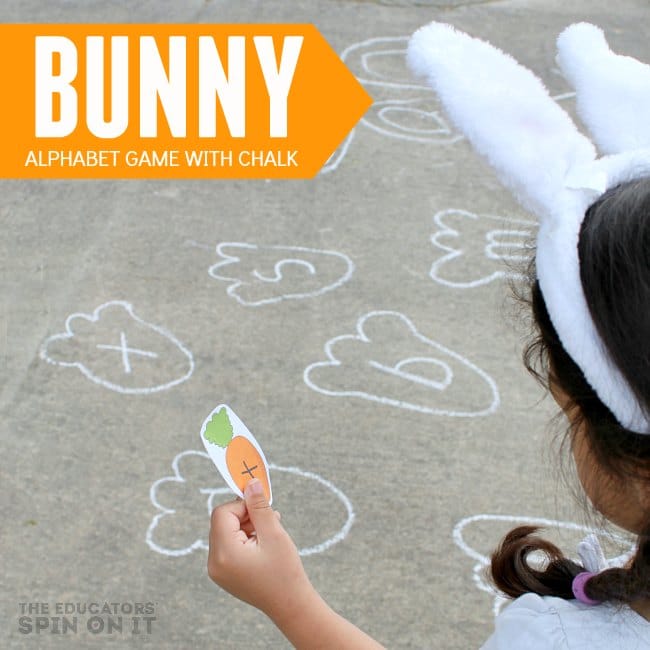 Bunny Alphabet Game with Chalk for Spring Movement Fun - The Educators' Spin On It child holding paper carrot with letter looking for rabbit foot print with sidewalk chalk outdoors.