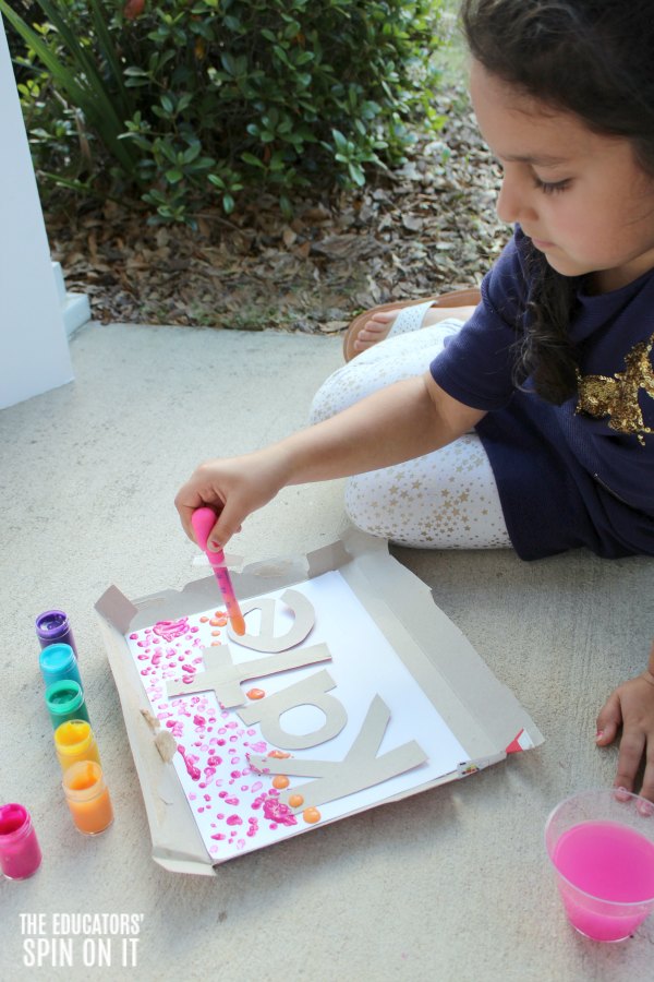Drip Rainbow Painting Name activity with Kids - The Educators' Spin On It Child drip painting with rainbow colored paints onto paper with stenciled name