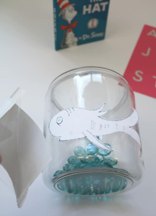fish-application-to-bowl-cat-in-the-hat-game - The Educators' Spin On It Large fishbowl with Dr. Seuss inspired fish being attaching with contact paper