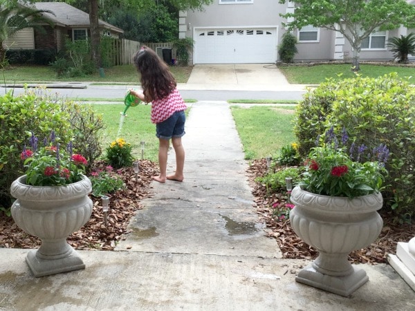 gardening-with-kids-front-porch - The Educators' Spin On It girl watering plants at front yard for butterfly garden