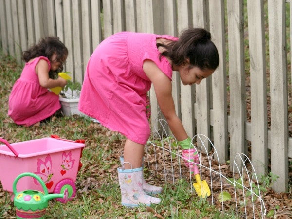 kids-in-backyard-gardening - The Educators' Spin On It two girls gardening in backyard with gardening tools near fence