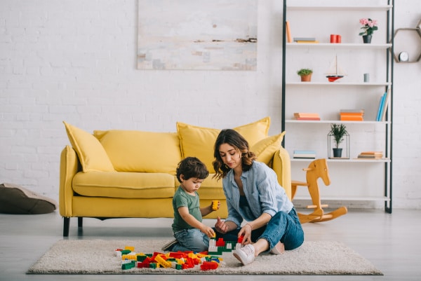 mom-playing-with-child-on-floor-with-toys - The Educators' Spin On It mother playing with son on carpet with legos while working at home