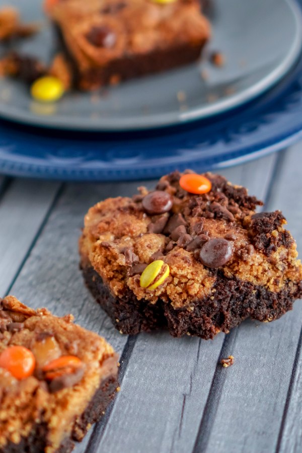 pumpkin-peanut-butter-brownies-with-candy-3 - The Educators' Spin On It Pumpkin Peanut Butter Brownie on Counter highlighting the candy toppings in yellow, orange and brown reeses pieces