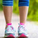 Closeup on shoe of athlete runner woman feet running on road